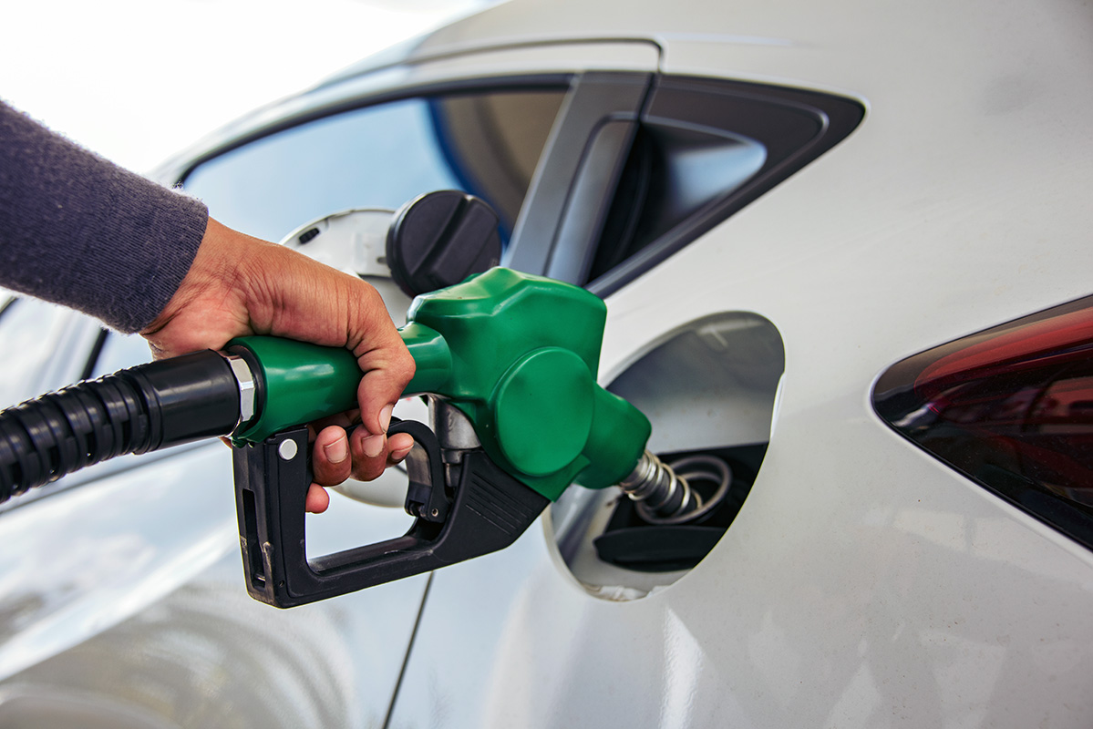 Hand refueling white car at gas station